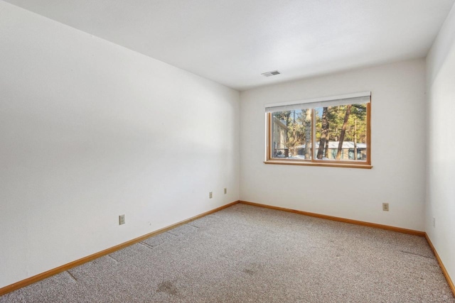 unfurnished room with carpet floors, visible vents, and baseboards