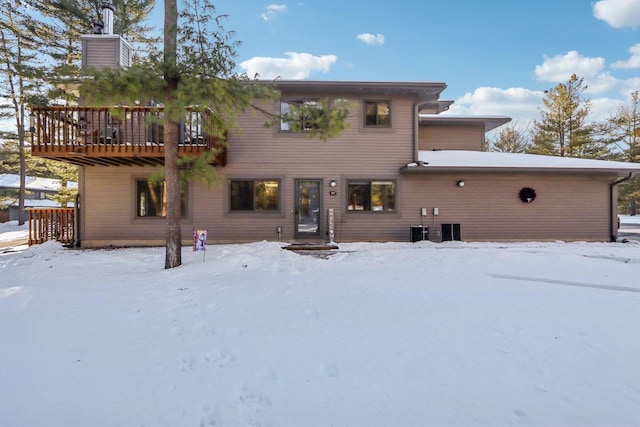 snow covered rear of property with a deck and central AC