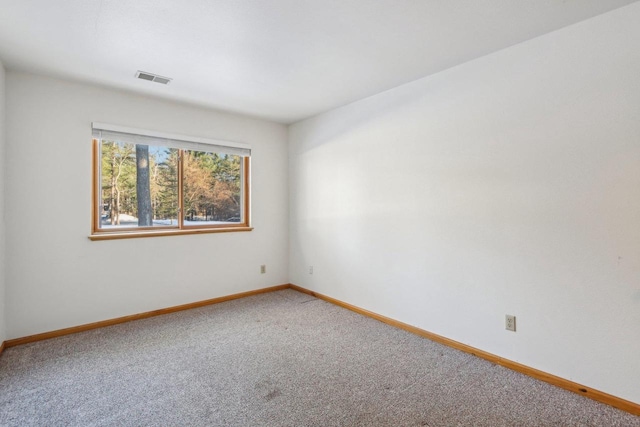 carpeted spare room featuring baseboards and visible vents