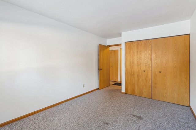 unfurnished bedroom featuring light carpet, a closet, and baseboards