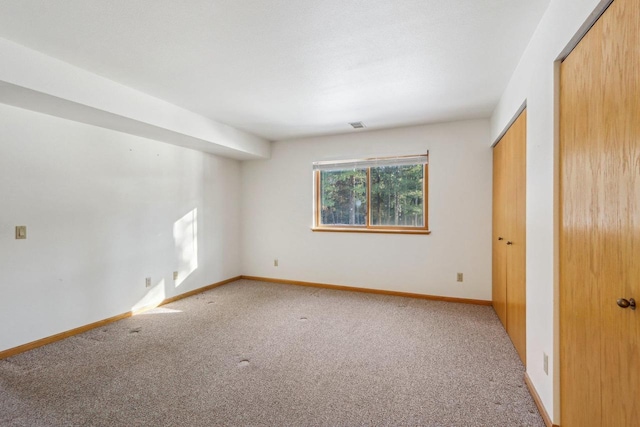 carpeted spare room featuring visible vents and baseboards