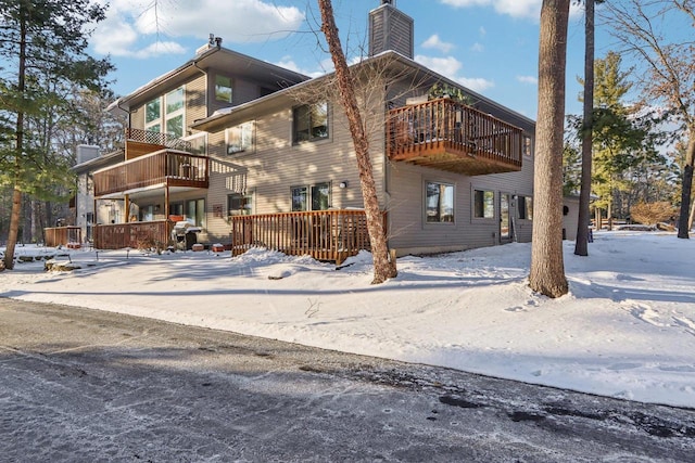 snow covered property with a chimney and a deck