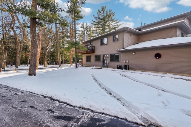 snow covered rear of property featuring a chimney