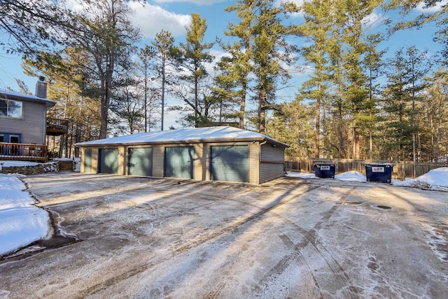 snow covered garage featuring fence