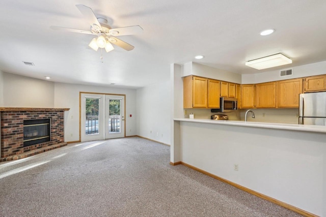 kitchen with stainless steel appliances, light countertops, visible vents, open floor plan, and light carpet