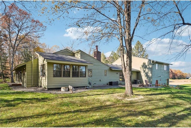 rear view of house featuring a yard, a chimney, a patio area, and central air condition unit