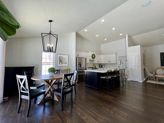 dining area featuring a notable chandelier, high vaulted ceiling, dark wood-type flooring, and recessed lighting