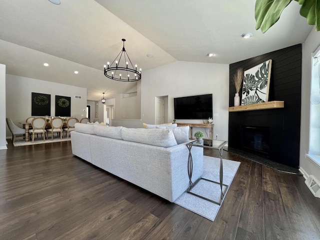 living room with a large fireplace, visible vents, dark wood finished floors, lofted ceiling, and a chandelier