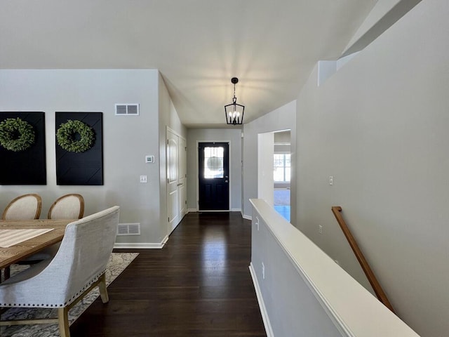 entryway with a notable chandelier, baseboards, visible vents, and dark wood-type flooring