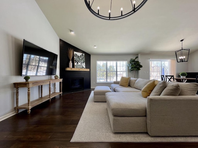 living room featuring a large fireplace, plenty of natural light, wood finished floors, and a notable chandelier