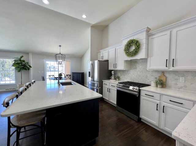 kitchen featuring a center island with sink, stainless steel appliances, white cabinets, a sink, and a kitchen breakfast bar