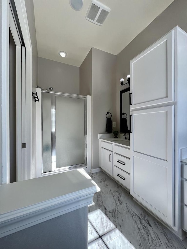 full bathroom with marble finish floor, vanity, a shower stall, and visible vents