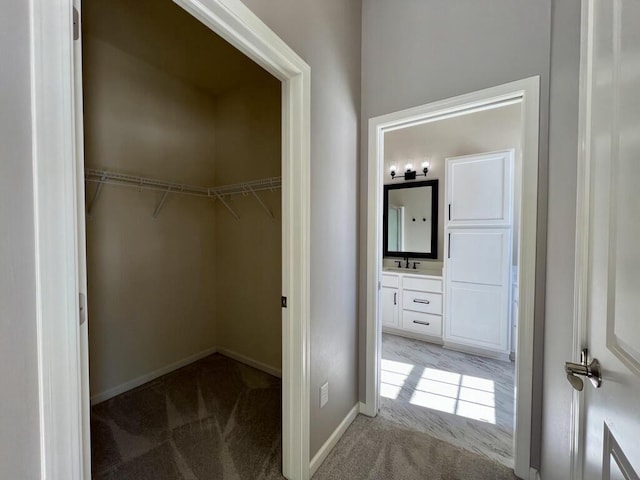 walk in closet featuring light carpet and a sink