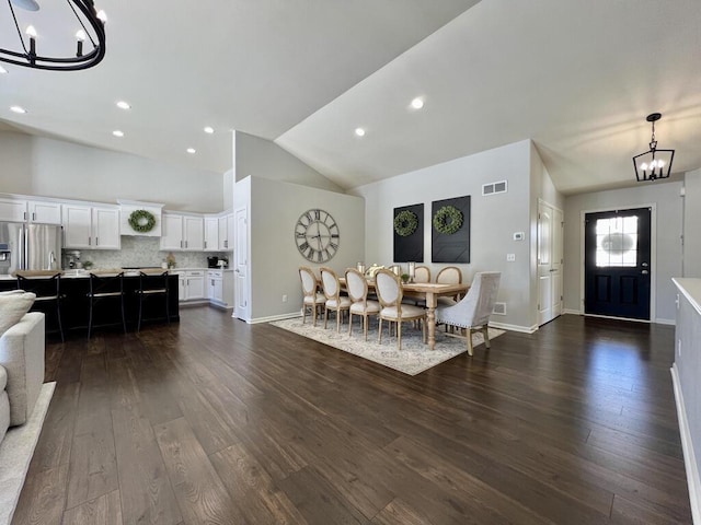 dining room featuring dark wood-style floors, lofted ceiling, visible vents, and a notable chandelier