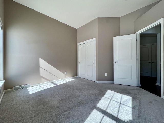 unfurnished bedroom with baseboards, visible vents, carpet, high vaulted ceiling, and a closet