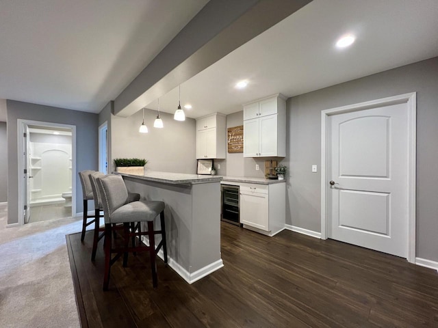 kitchen with beverage cooler, a kitchen bar, white cabinetry, and pendant lighting