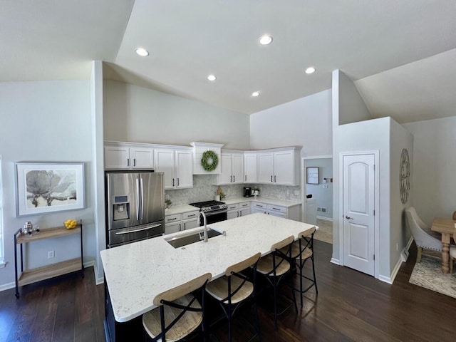 kitchen featuring stainless steel appliances, white cabinets, a center island with sink, and a sink