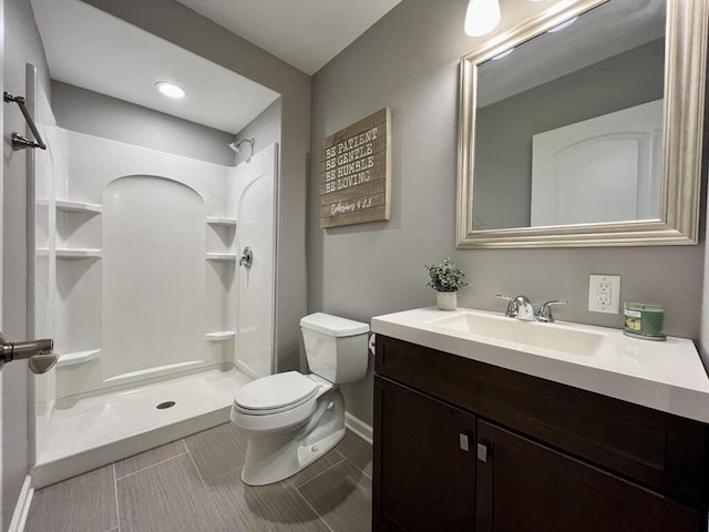 full bath with vanity, a shower stall, toilet, and baseboards