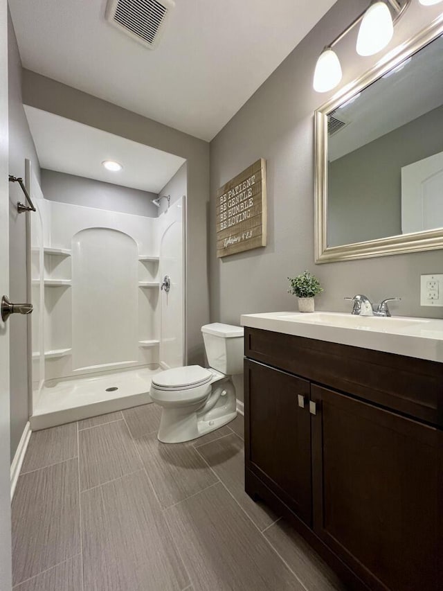 full bath featuring visible vents, baseboards, toilet, vanity, and a shower stall