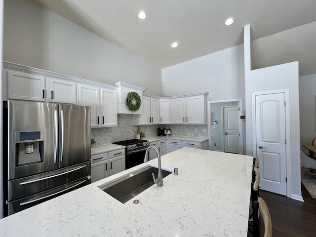 kitchen featuring stainless steel appliances, white cabinetry, a sink, and light stone countertops