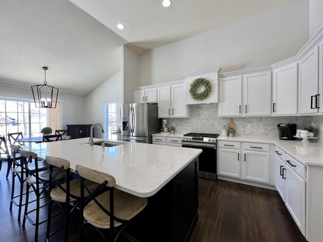 kitchen with a kitchen island with sink, a sink, white cabinetry, hanging light fixtures, and appliances with stainless steel finishes