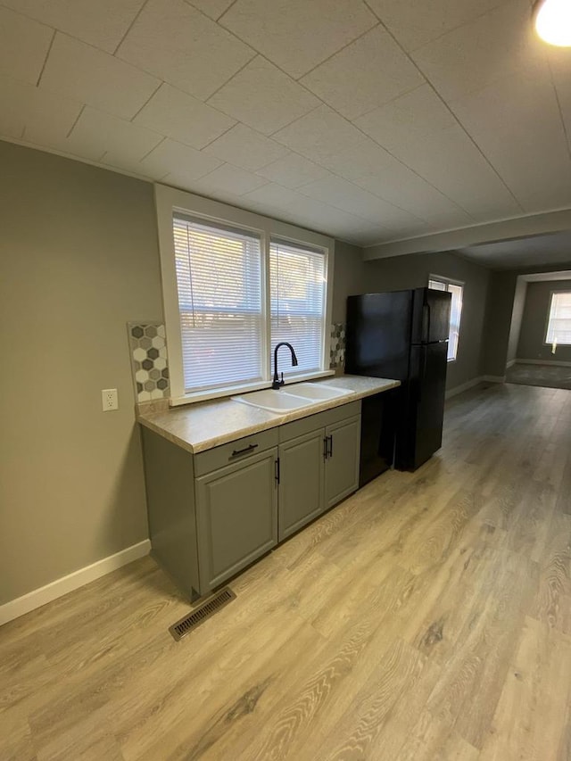 kitchen with visible vents, freestanding refrigerator, light countertops, light wood-style floors, and a sink