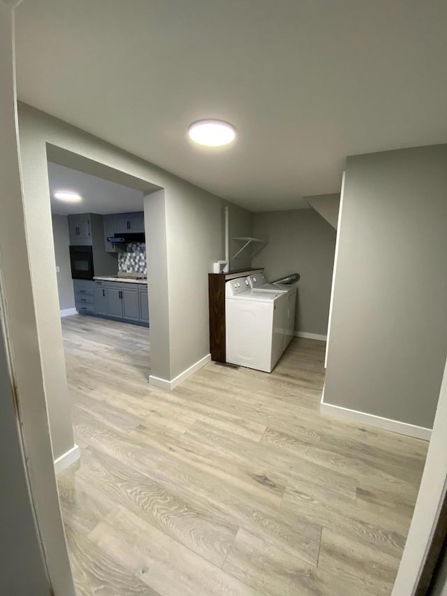 washroom featuring laundry area, light wood finished floors, independent washer and dryer, and baseboards