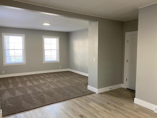 unfurnished room with light wood-type flooring and baseboards