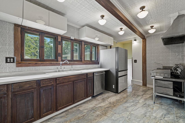 kitchen featuring dark brown cabinetry, wall chimney exhaust hood, appliances with stainless steel finishes, light countertops, and a sink