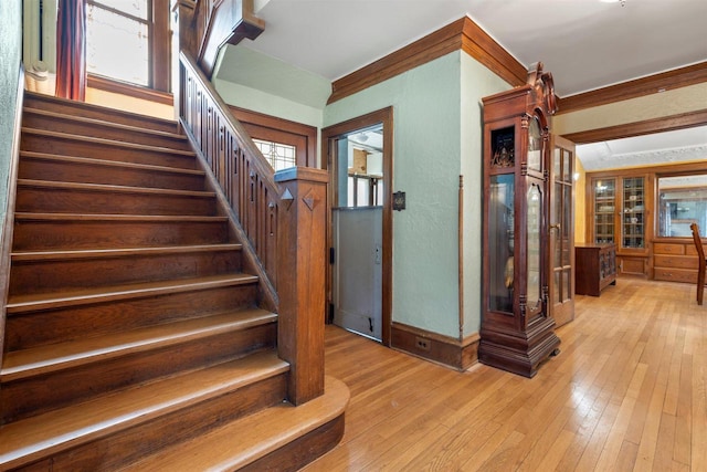 stairway with baseboards, wood finished floors, and ornamental molding