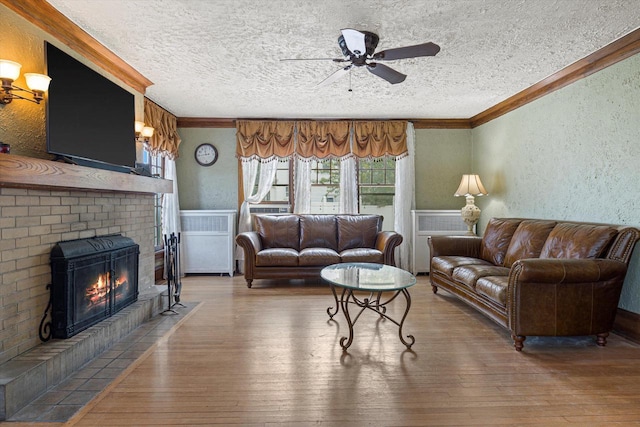 living room with ornamental molding, wood finished floors, and a textured wall