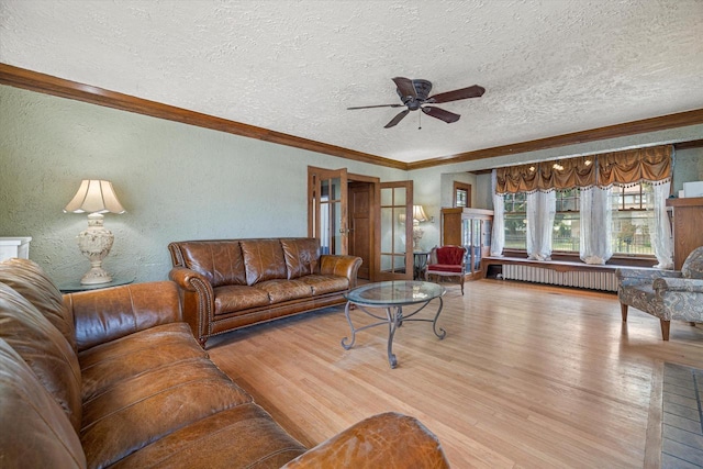 living room with ornamental molding, light wood-type flooring, a textured wall, and radiator heating unit