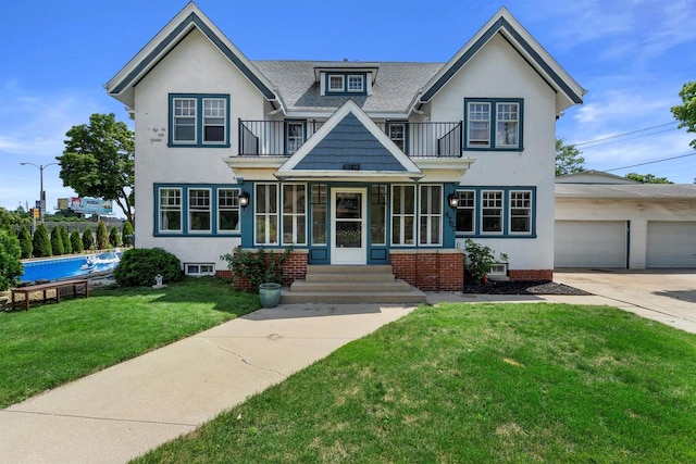 view of front of property featuring a balcony, a garage, concrete driveway, stucco siding, and a front yard