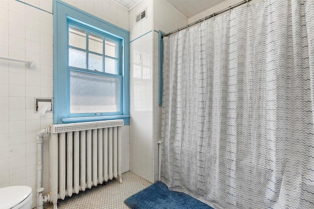 full bathroom featuring visible vents, toilet, tile walls, and radiator