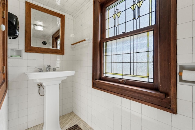 bathroom featuring plenty of natural light and tile walls