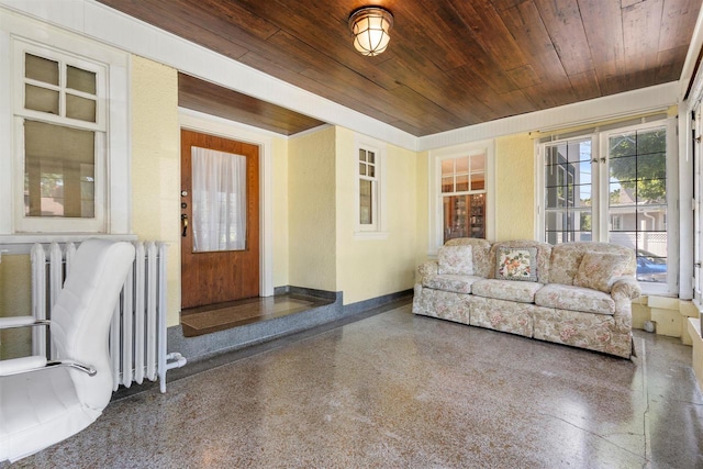 living room with wooden ceiling, baseboards, radiator heating unit, and speckled floor