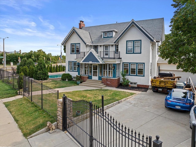 view of front of home with a balcony, a fenced front yard, a gate, and stucco siding