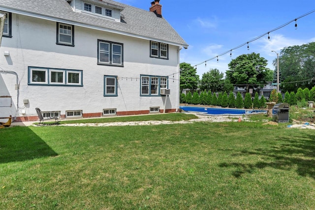 back of property featuring a chimney, cooling unit, a lawn, and roof with shingles