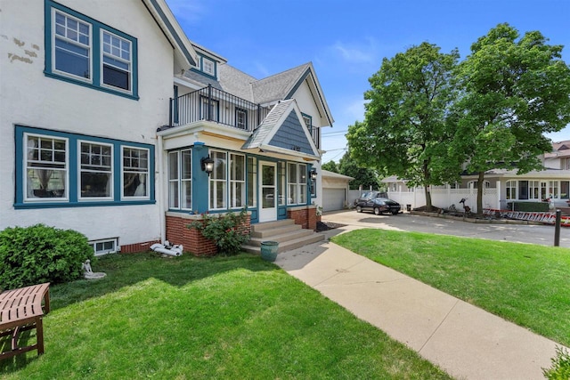 view of front of home with a balcony, a front lawn, and stucco siding