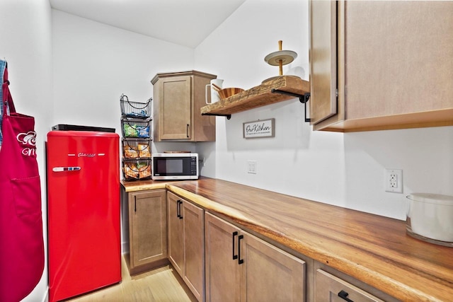 kitchen featuring butcher block countertops, stainless steel microwave, open shelves, and refrigerator