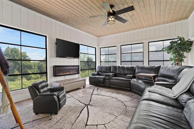 living room with wooden ceiling, ceiling fan, wood finished floors, and a glass covered fireplace