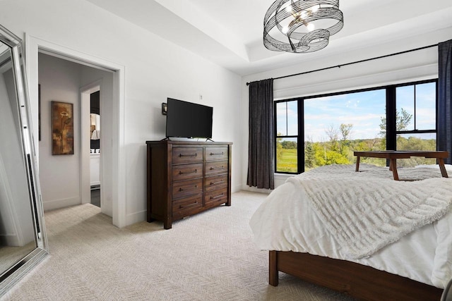 bedroom with light carpet, a raised ceiling, and baseboards