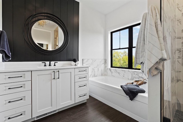 bathroom with a garden tub, visible vents, wood finished floors, and vanity