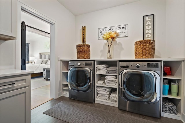 laundry room with wood finished floors, cabinet space, separate washer and dryer, and a barn door