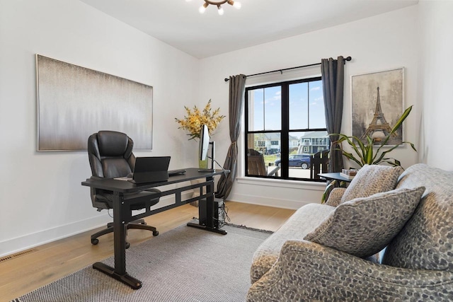 office space featuring light wood-type flooring, visible vents, and baseboards