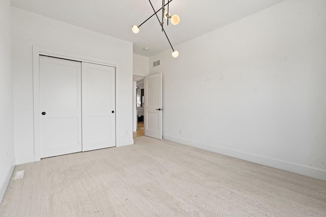 unfurnished bedroom with visible vents, a closet, light colored carpet, and baseboards