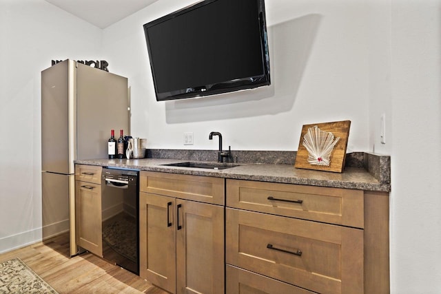 kitchen with light wood-style flooring, a sink, brown cabinets, dishwasher, and dark countertops