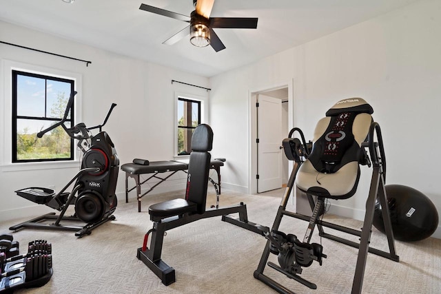 exercise area featuring light carpet and baseboards