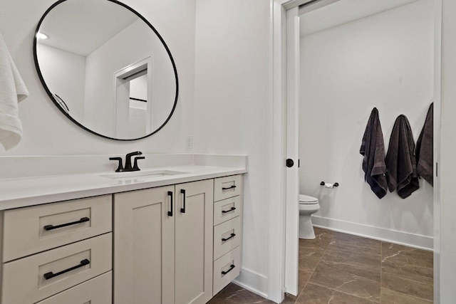 bathroom featuring toilet, marble finish floor, baseboards, and vanity