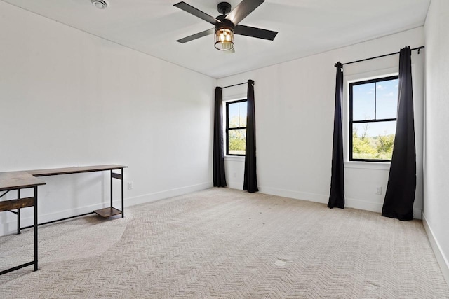 empty room with light carpet, ceiling fan, a wealth of natural light, and baseboards